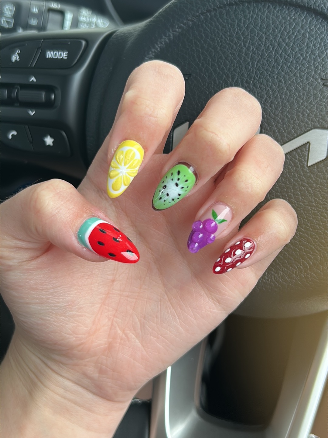 Fruit themed nail art across five nails: lemon, kiwi, watermelon, grapes and strawberry