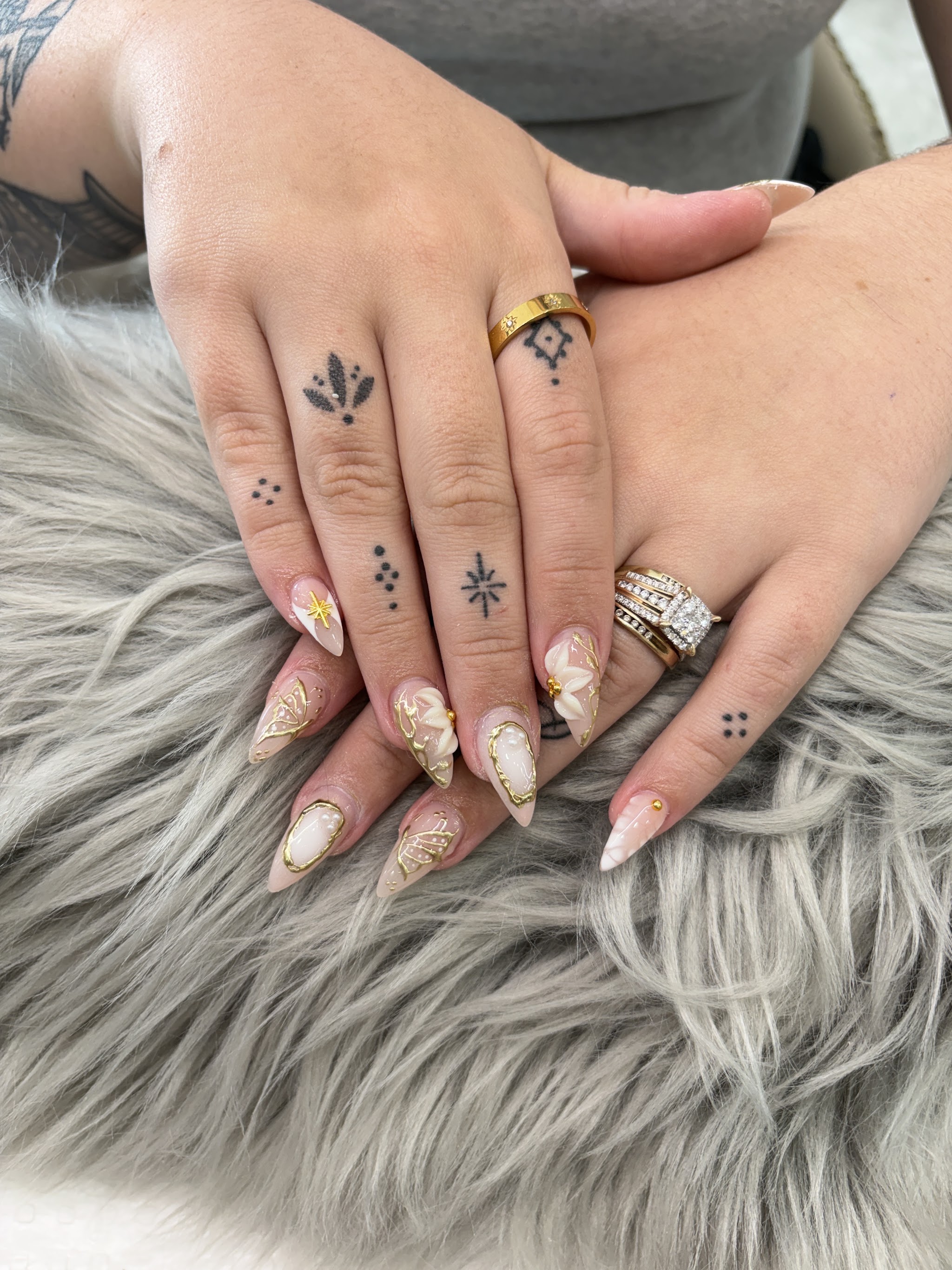 Nude and white almond nails finished with 3D gold butterfly and floral accents